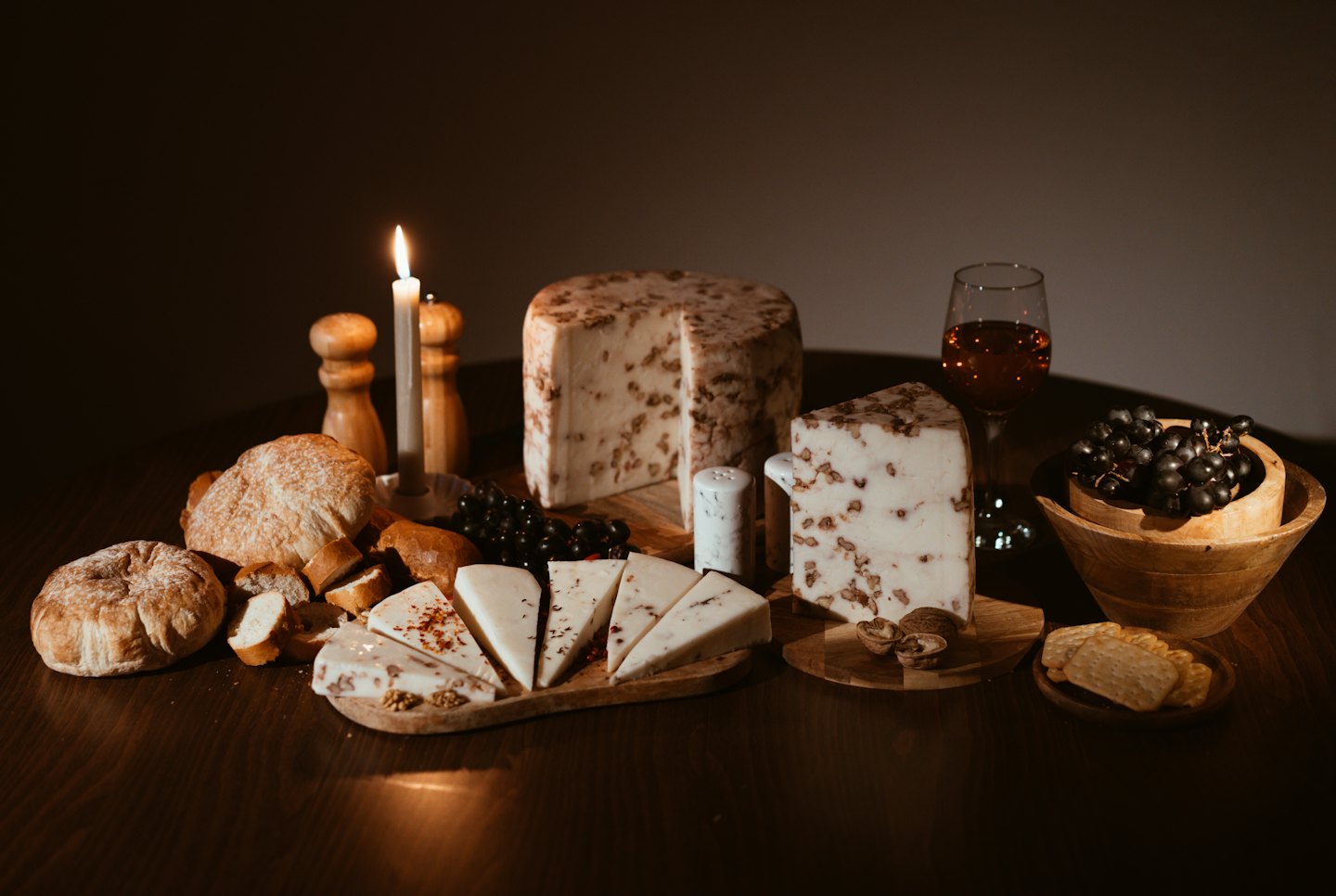 Cheese and bread spread with red wine and grapes on a table.