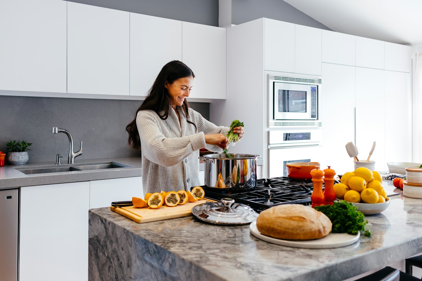 Woman happily prepares healthy food in a modern kitchen.