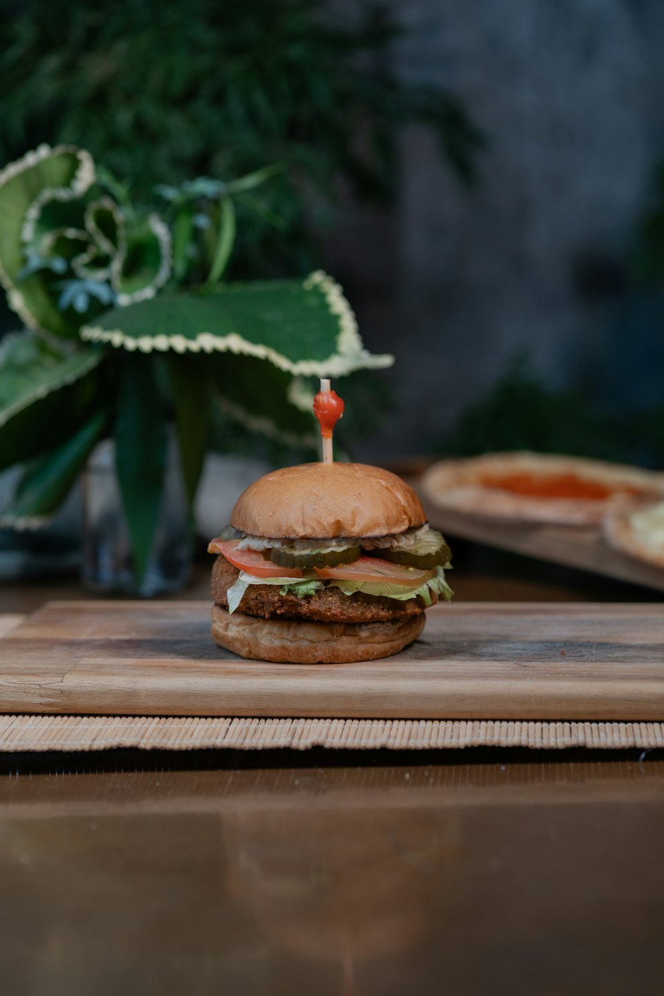 Plant-based burger with fresh toppings on a wooden board.